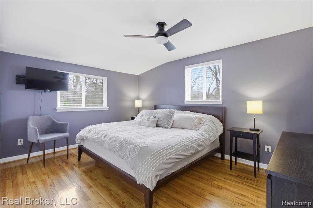 Bedroom featuring light wood-type flooring, a ceiling fan, lofted ceiling, and multiple windows