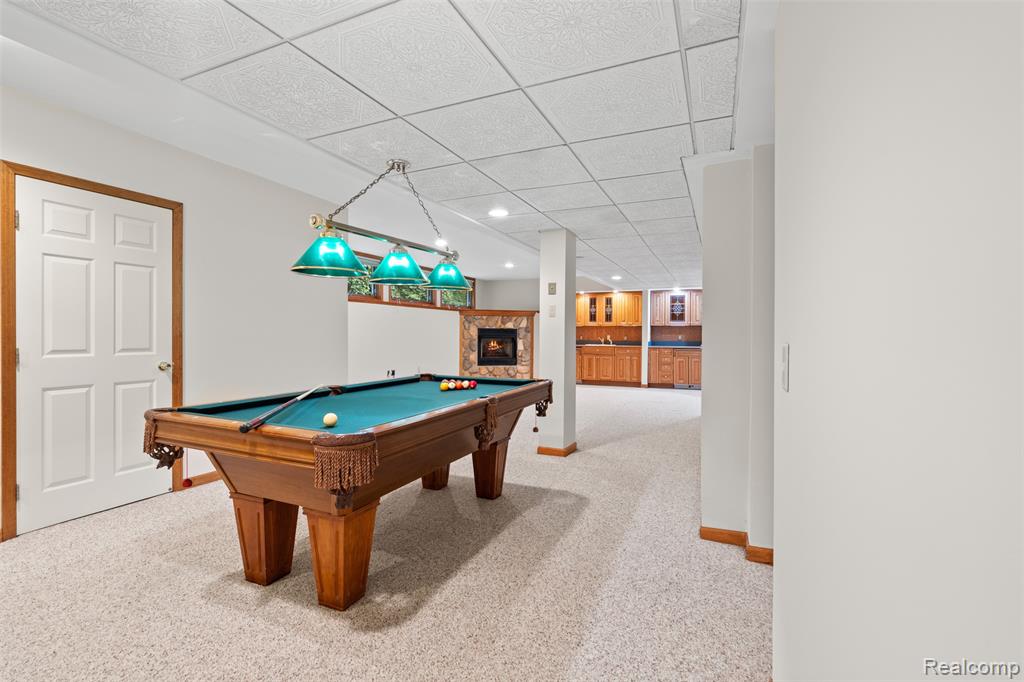 Recreation room featuring a drop ceiling, billiards table, light colored carpet, a glass covered fireplace, and recessed lighting