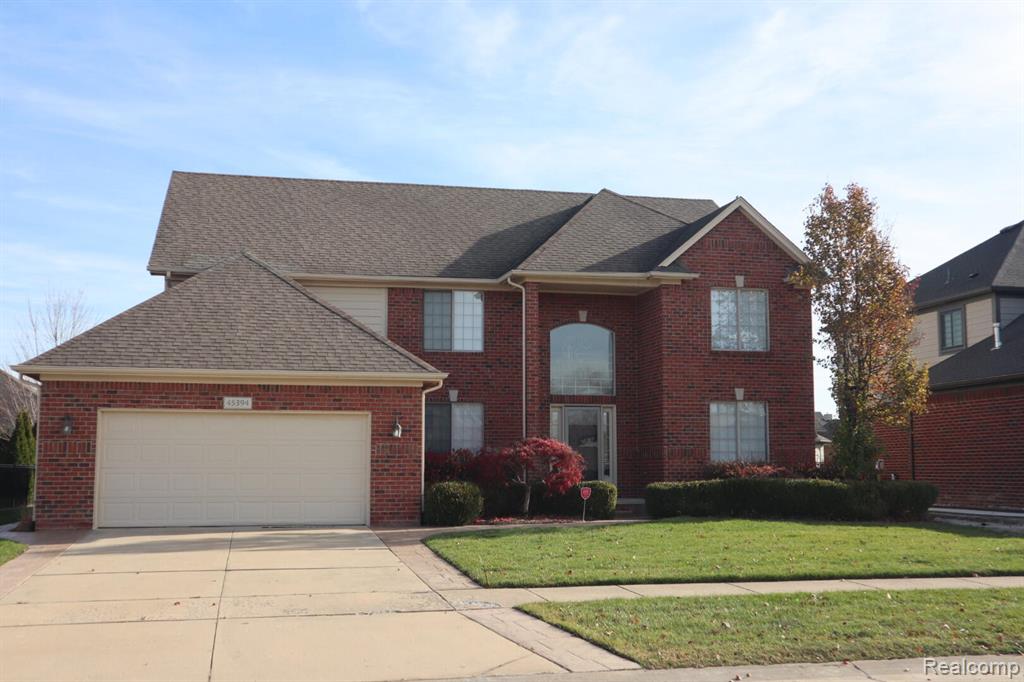View of front facade with a garage, a front lawn, concrete driveway, and roof with shingles