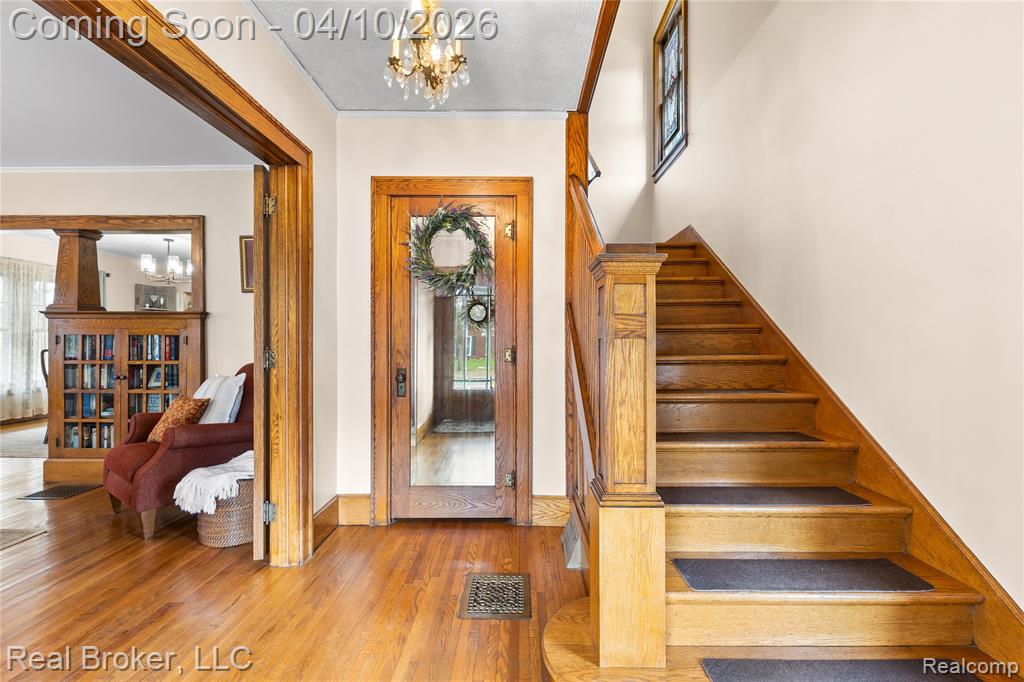 Entryway featuring suspended lighting, ornamental molding, and light wood-type flooring