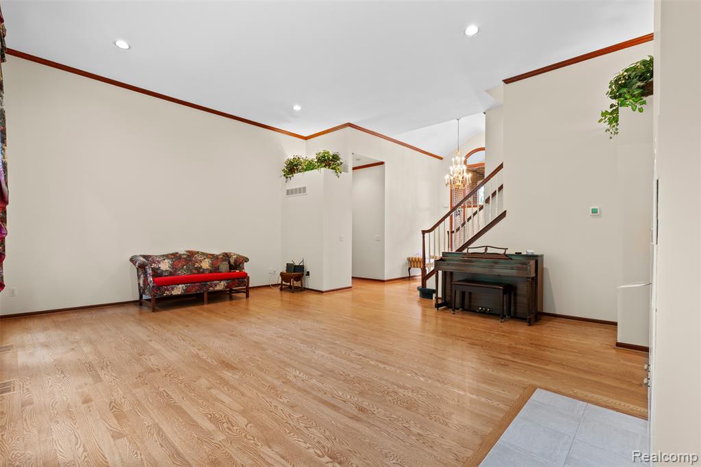 Living area with light wood finished floors, recessed lighting, stairway, a chandelier, and ornamental molding