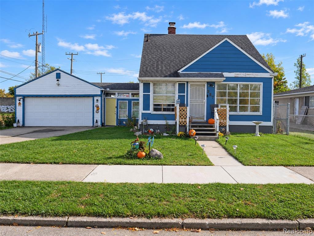 Blue exterior siding, asphalt shingle roof, attached garage, large picture windows, and concrete walkway