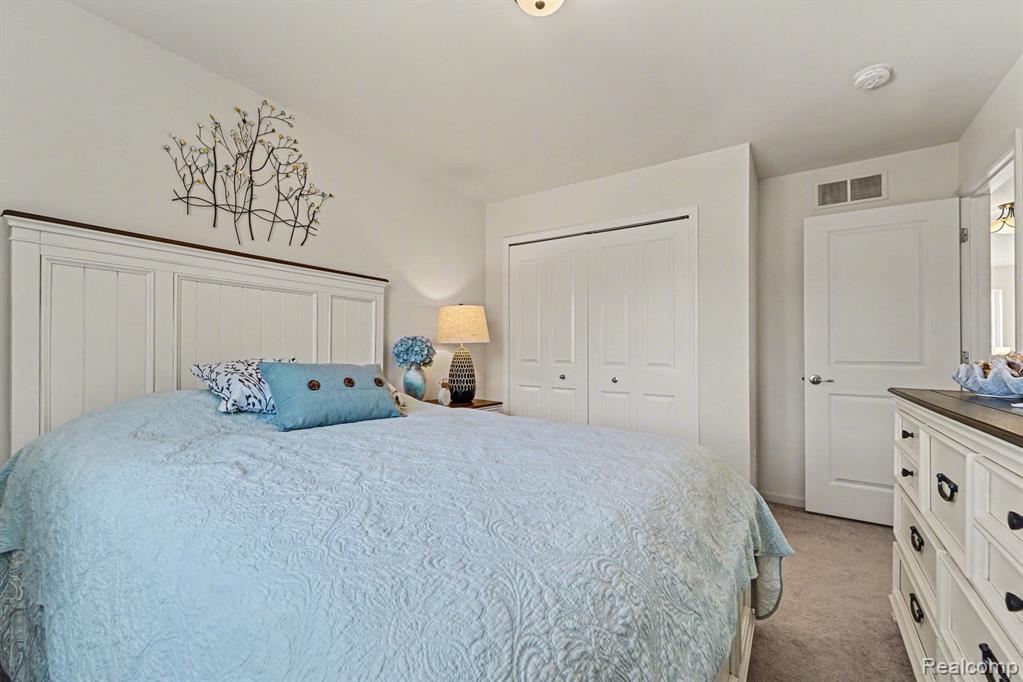 Bedroom with light carpet and a closet