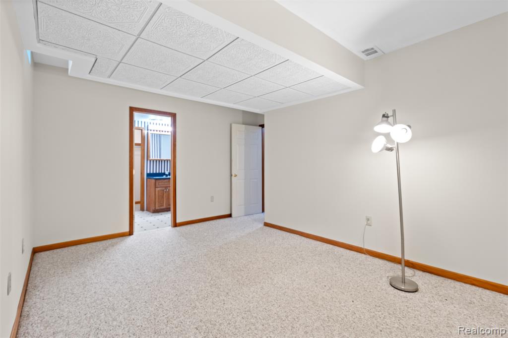 Carpeted spare room featuring baseboards and a paneled ceiling