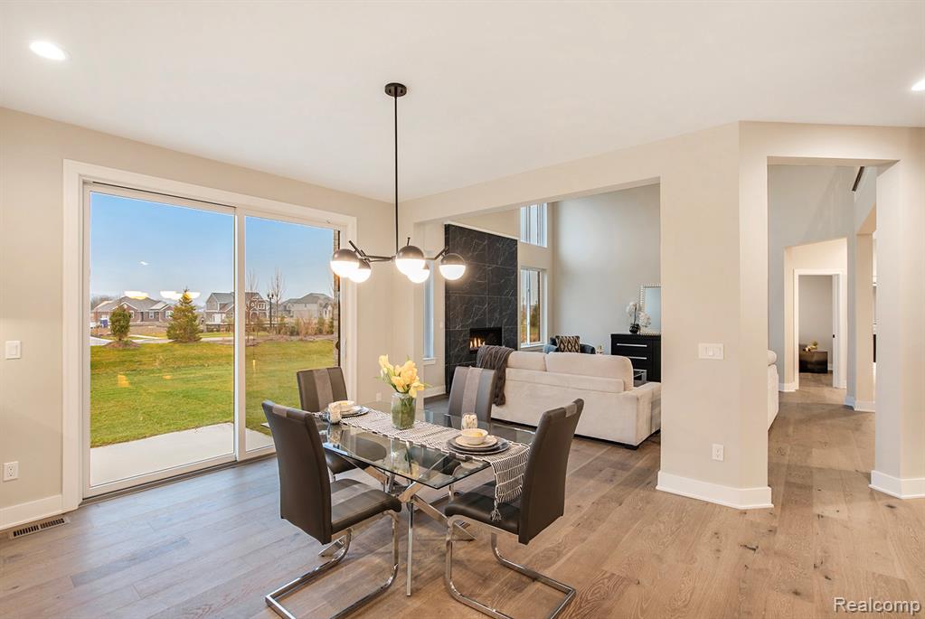 Dining area with a high end fireplace, recessed lighting, light wood finished floors, a chandelier, and a residential view