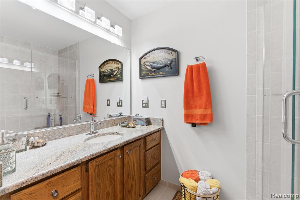 Bathroom with a shower stall, vanity, and light tile patterned flooring