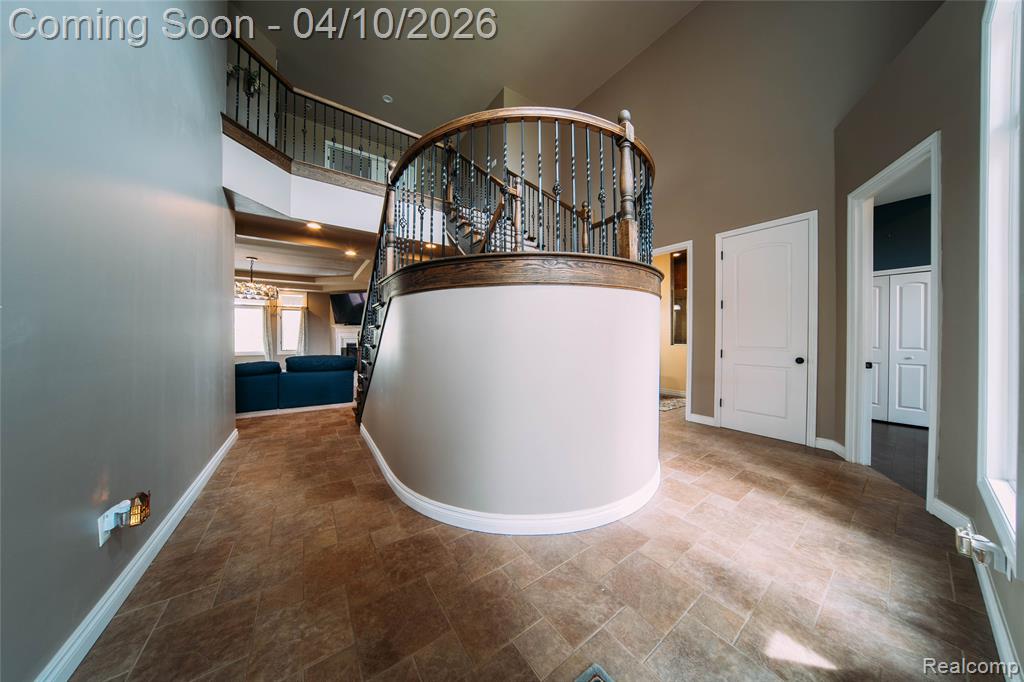 Corridor with a high ceiling, stone finish flooring, and a chandelier