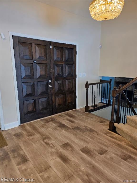 Entrance foyer featuring wood finished floors, stairway, and a chandelier