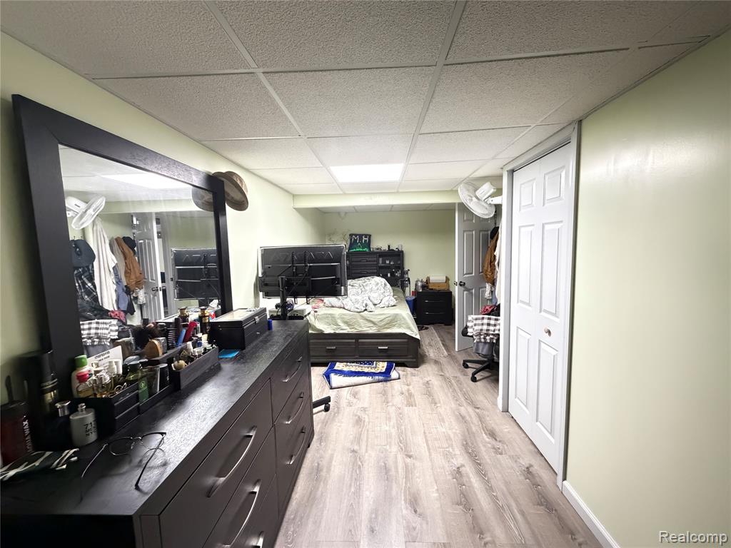 Bedroom featuring light wood-style flooring and a drop ceiling