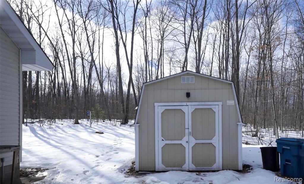 Snow covered structure featuring a storage shed