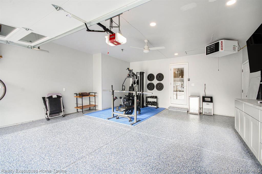 Garage with a heating unit, a ceiling fan, a garage door opener, and recessed lighting