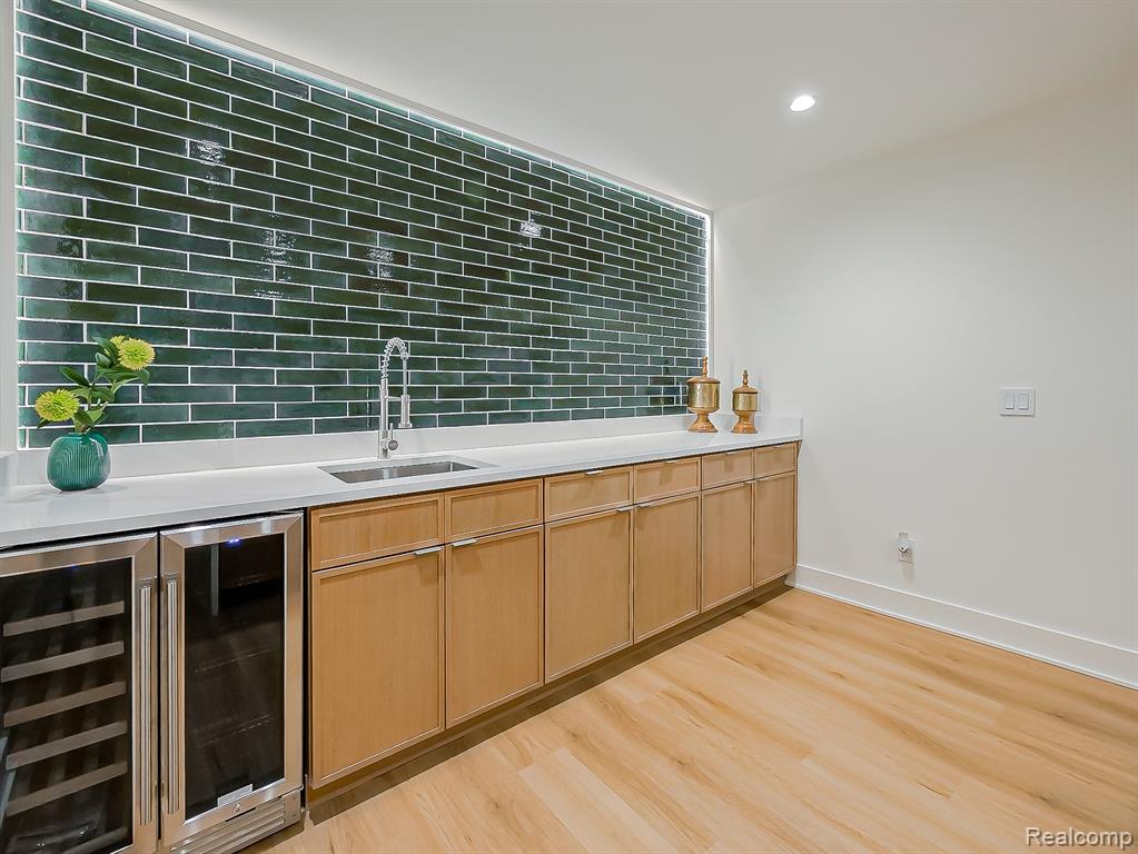 Bar with wine cooler, light wood-style floors, light brown cabinets, recessed lighting, and light stone countertops