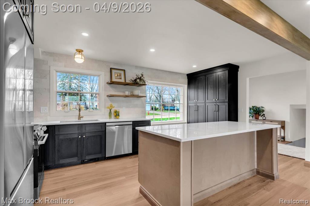 Kitchen with stainless steel appliances, light wood-style flooring, a kitchen island, light stone counters, and recessed lighting