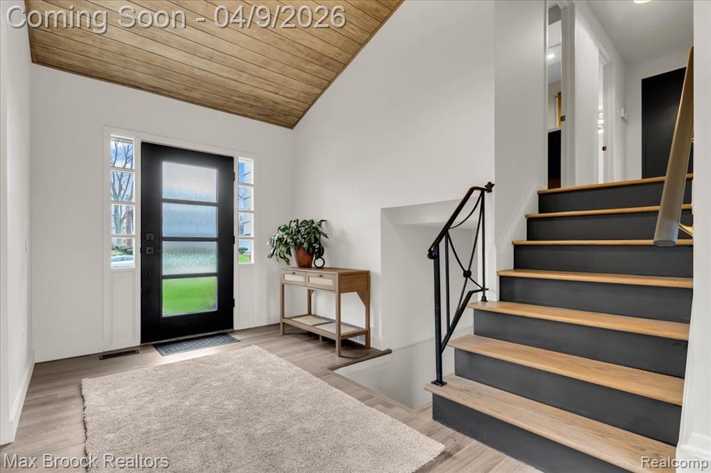 Entrance foyer with light wood-style floors and a vaulted wooden ceiling