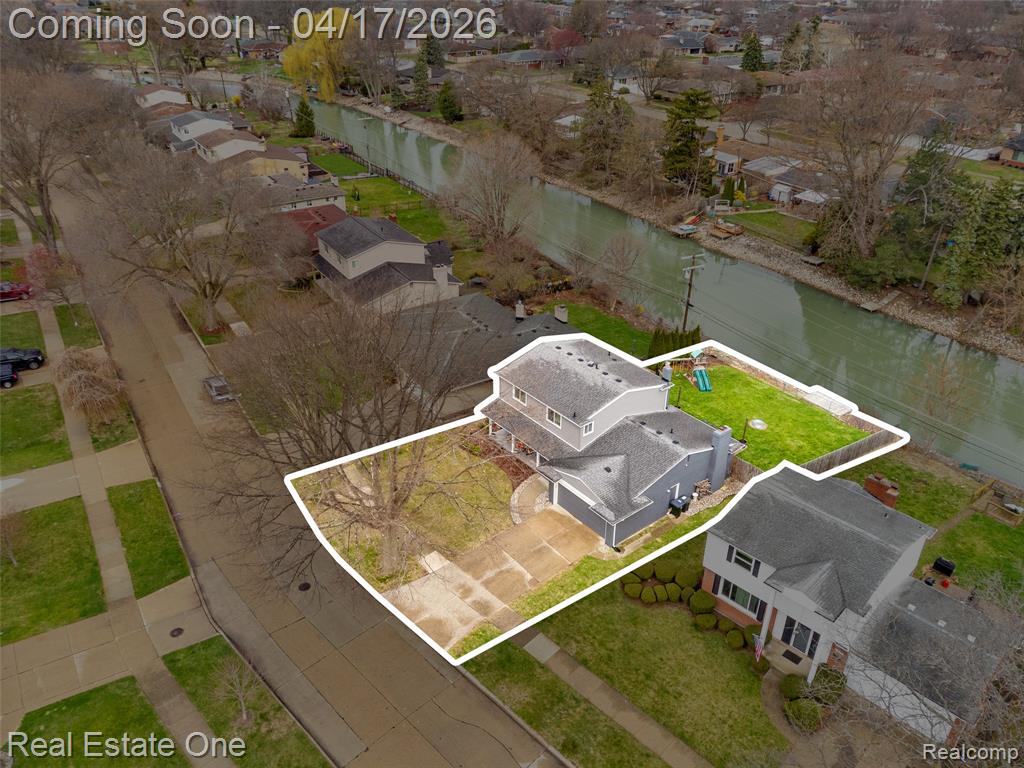 Aerial perspective of suburban area with property parcel outlined and a nearby body of water