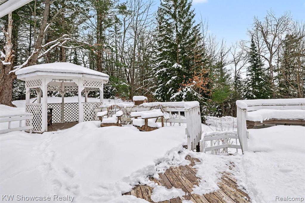 Snowy yard featuring a wooden deck and a gazebo