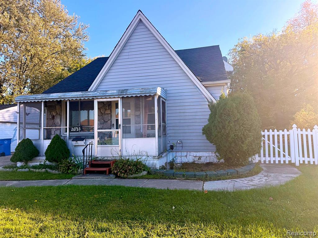 Exterior featuring blue horizontal siding, stone veneer accents, a covered screened-in front porch, and a white picket fence