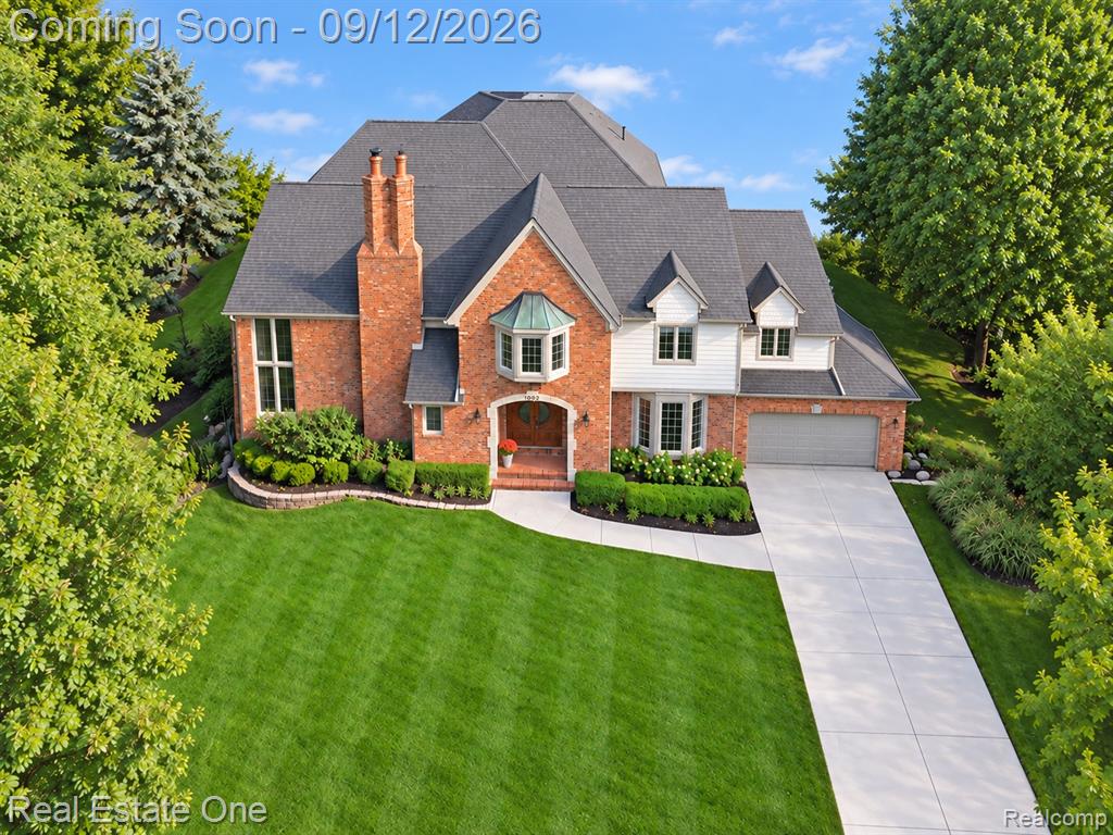 Brick and siding exterior with a multi-gabled roof, extensive landscaping, and a concrete driveway