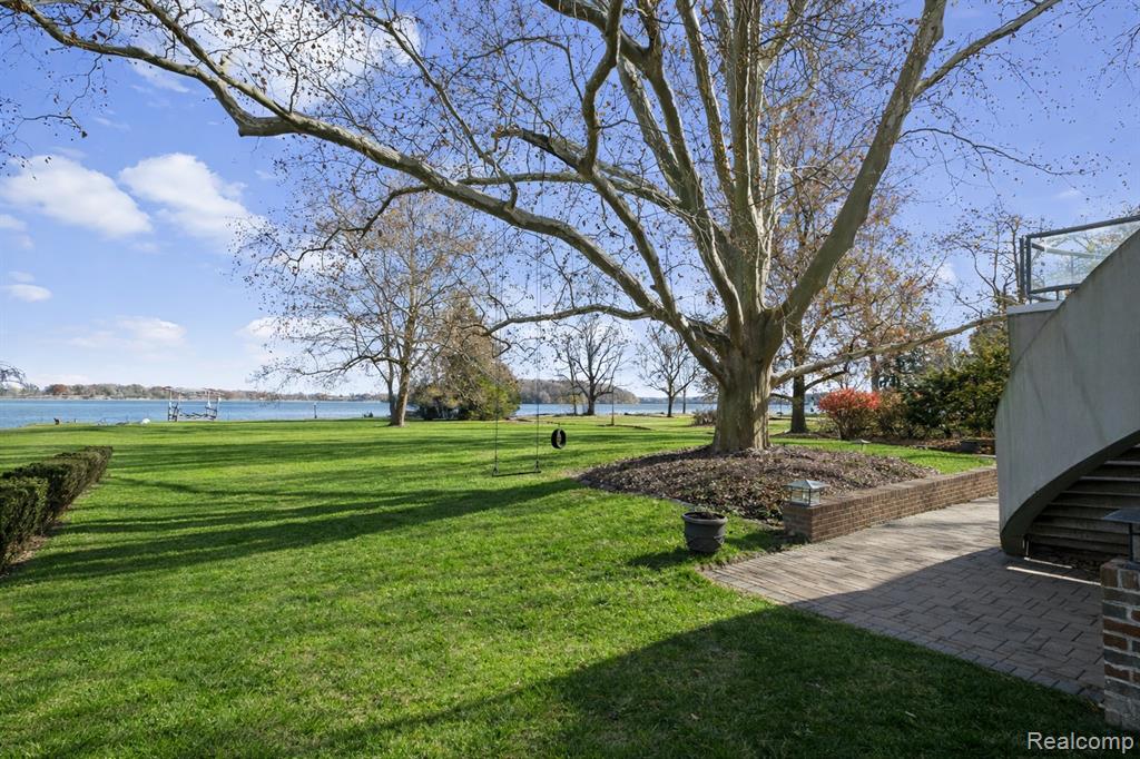 View of green lawn featuring a water view, stairway, and a patio area
