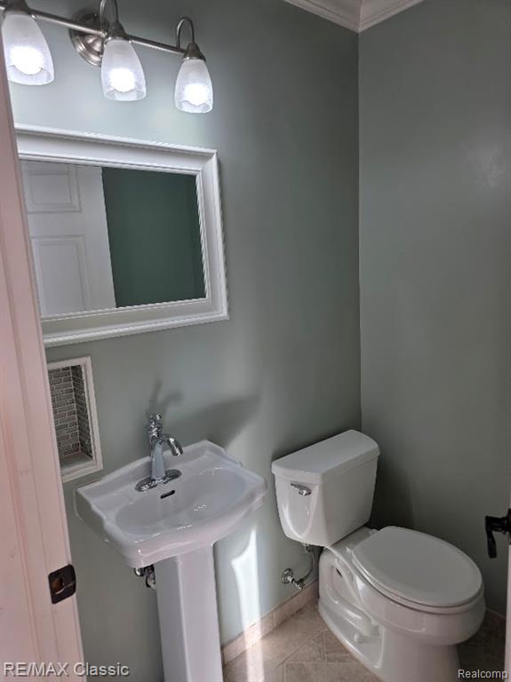 Half bathroom featuring tile patterned flooring and ornamental molding