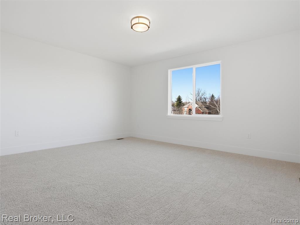 Carpeted spare room featuring baseboards