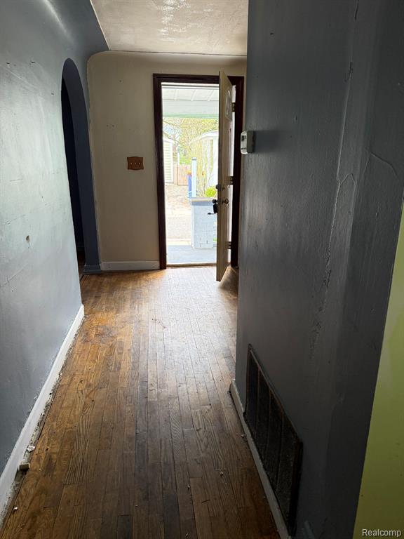 Hallway with dark wood-type flooring and arched walkways