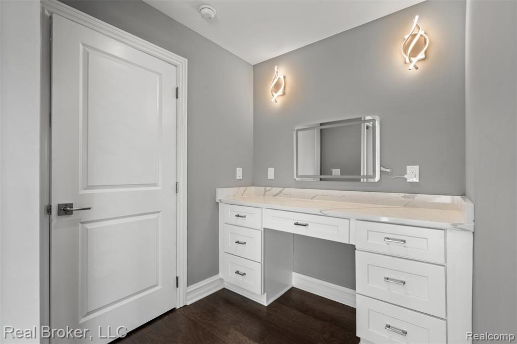 Master with vanity and dark wood finished floors