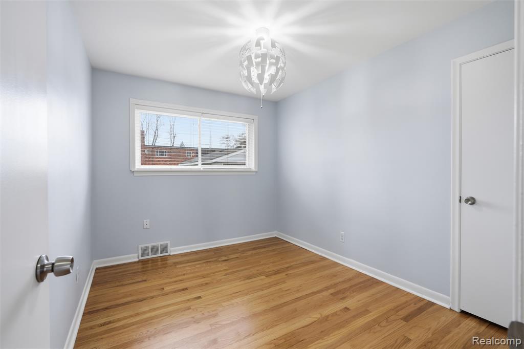 Empty room with light wood finished floors and hanging lights