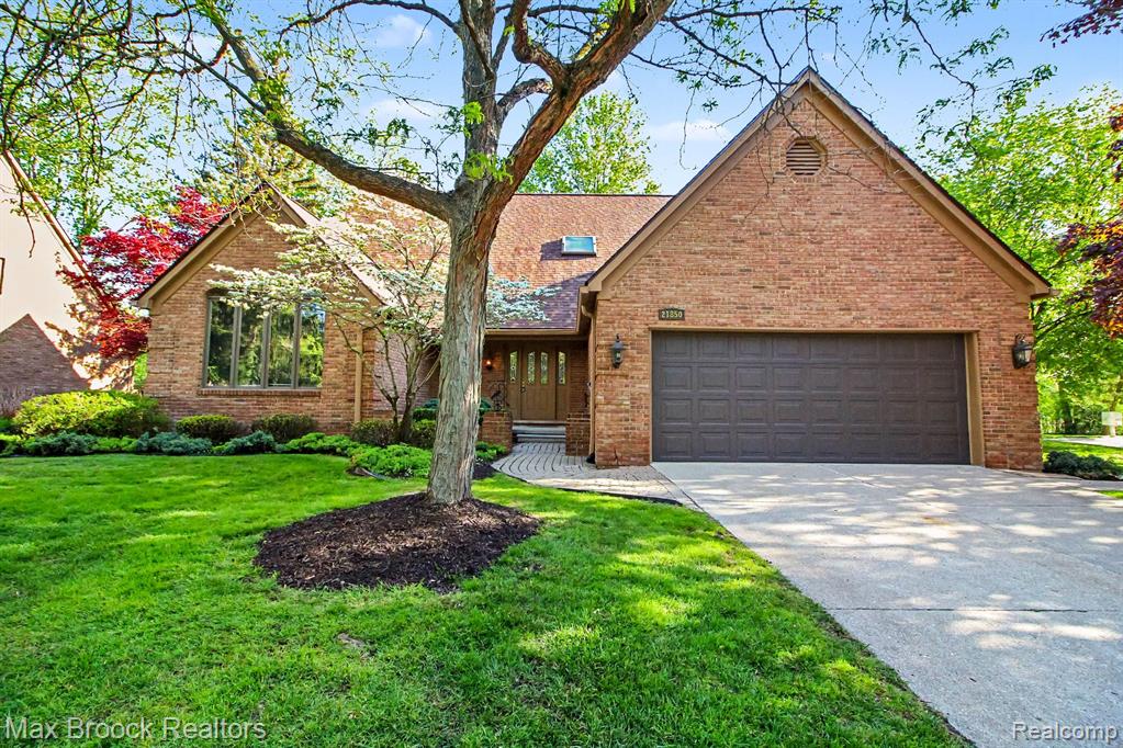 View of front of house featuring an attached garage, driveway, a front lawn, and brick siding
