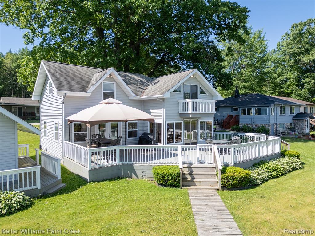 Back of property featuring a wooden deck, a lawn, and outdoor dining area