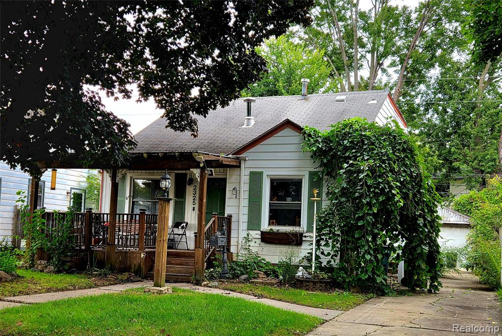 Wood-clad siding with contrasting trim, a covered front porch, and a paved driveway