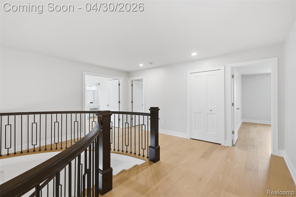 Corridor with light wood-style floors, an upstairs landing, and recessed lighting