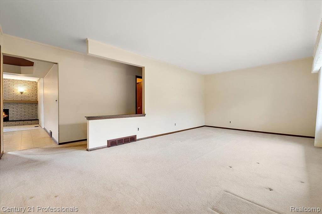 Spare room with carpet floors, a fireplace, and brick wall