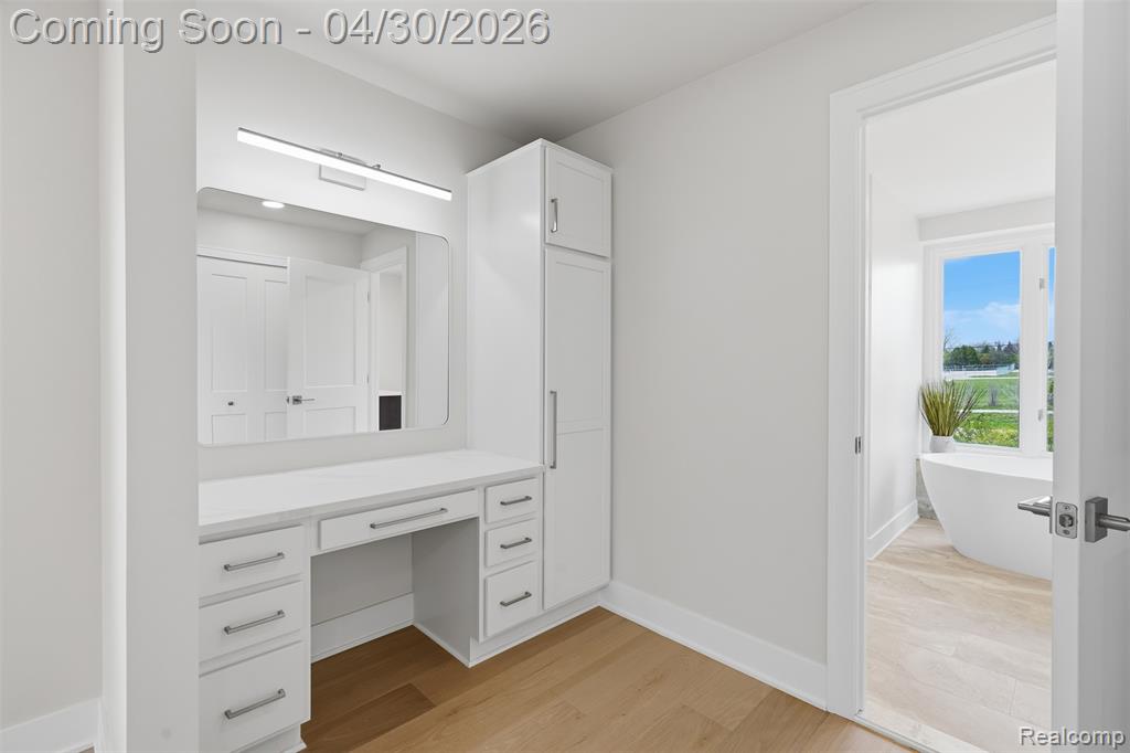 Primary bath sitting area with vanity, light wood flooring