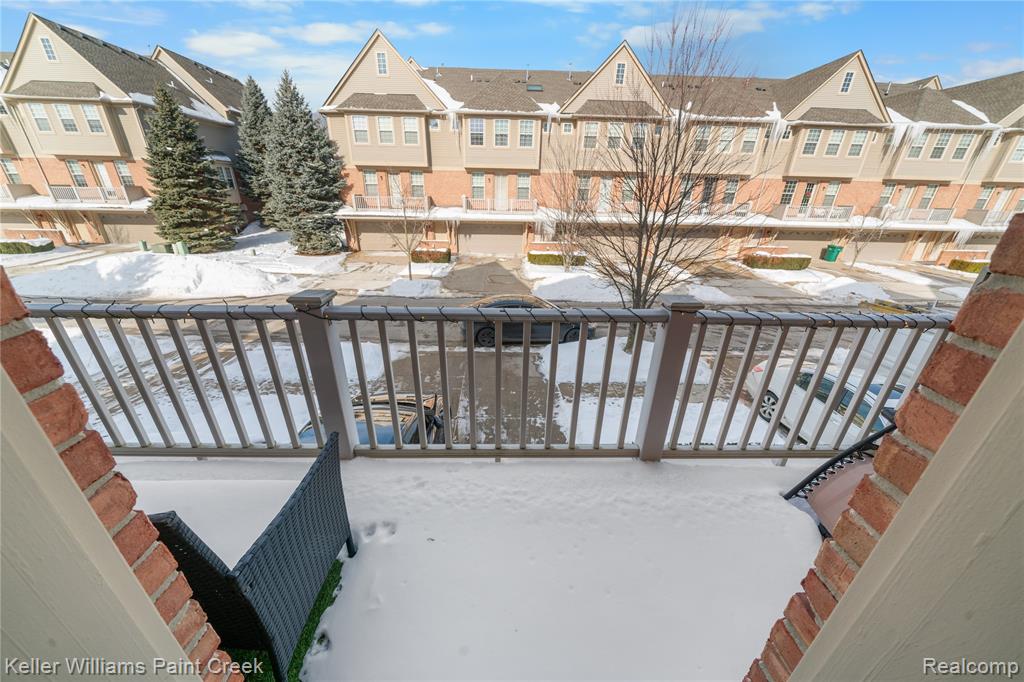 Snow covered back of property featuring a residential view