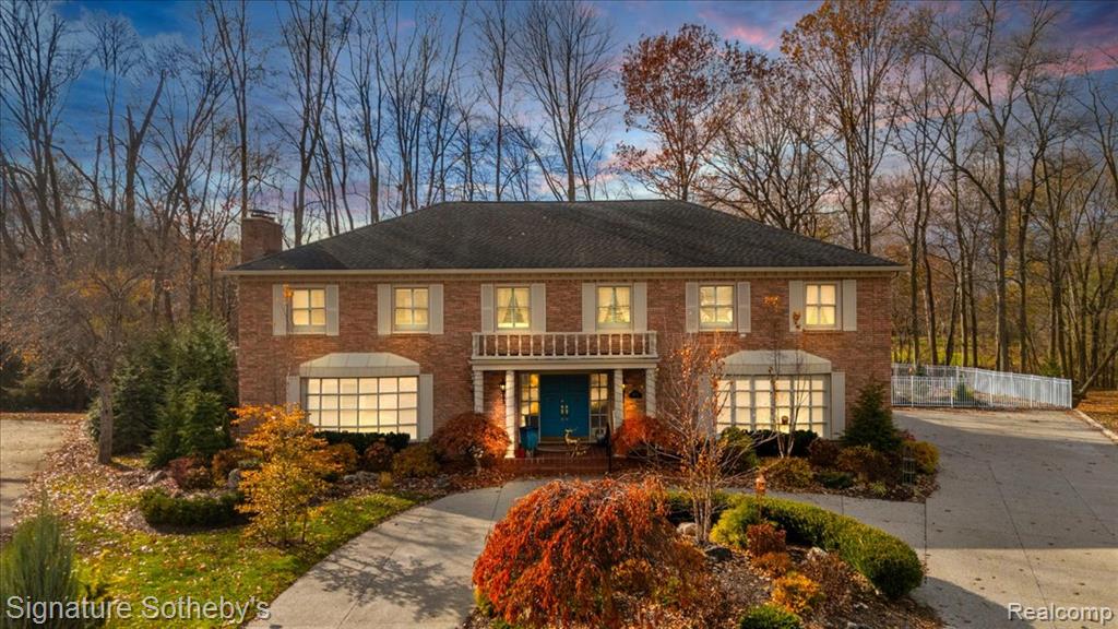 Photo for 38383 Saddle Lane, Clinton Twp, MI 48036 - listing #20251054218 Georgian-style home featuring a chimney, brick siding, concrete driveway, and covered porch