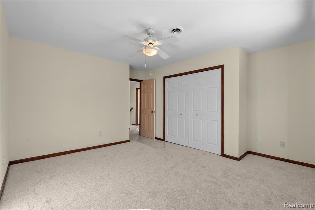 Unfurnished bedroom featuring carpet, a closet, and a ceiling fan