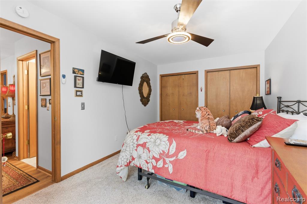 Bedroom with multiple closets, a ceiling fan, and light carpet