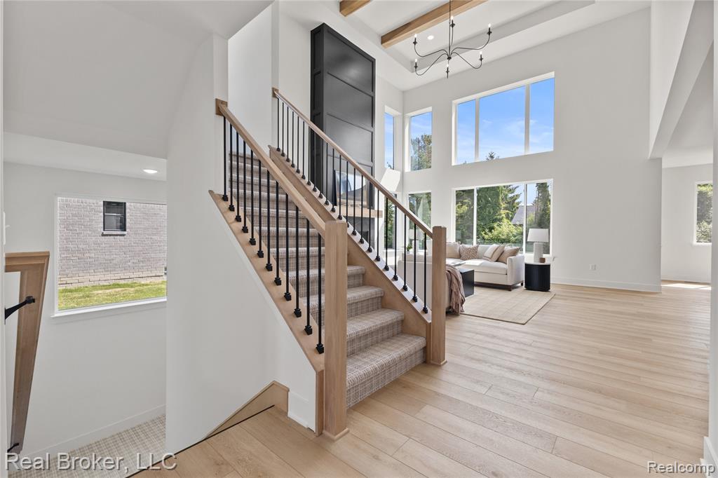 Stairway featuring healthy amount of natural light, hardwood / wood-style floors, beamed ceiling, a chandelier, and recessed lighting