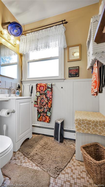 Bathroom with vanity, a baseboard heating unit, and a wainscoted wall