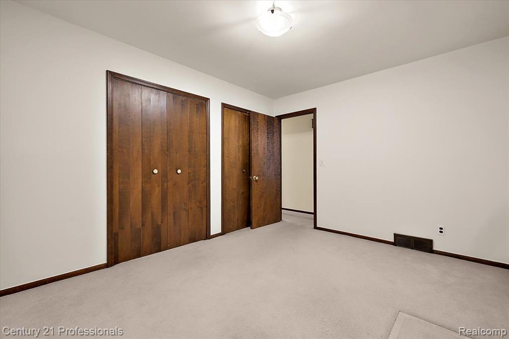 Unfurnished bedroom with two closets and carpet