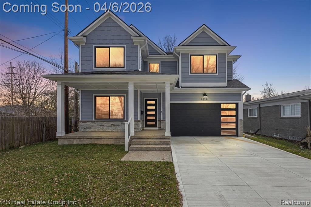 View of front of home featuring a porch, concrete driveway, a garage, and stone siding