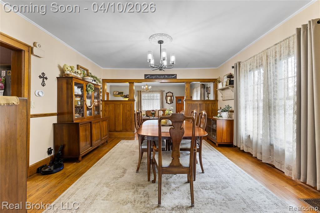 Dining area featuring suspended lighting, crown molding, and light wood finished floors