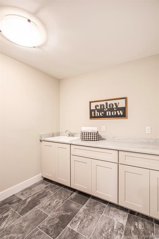 Laundry room featuring baseboards and dark marble finish flooring