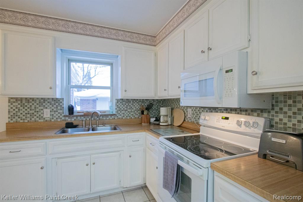 Kitchen with white electric range oven, white cabinetry, light countertops, and light tile patterned floors