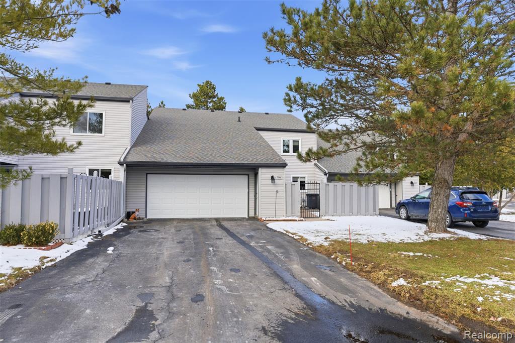 View of front of house with a gate, roof with shingles, driveway, and an attached garage