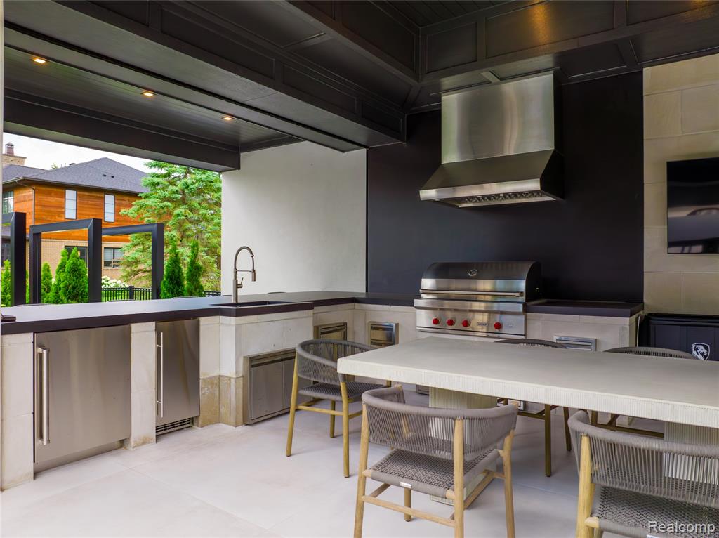 Kitchen with stainless steel refrigerator, under cabinet range hood, and dark countertops