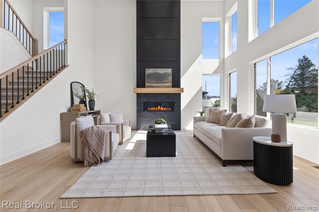 Living area featuring stairs, a high ceiling, a tiled fireplace, and wood finished floors
