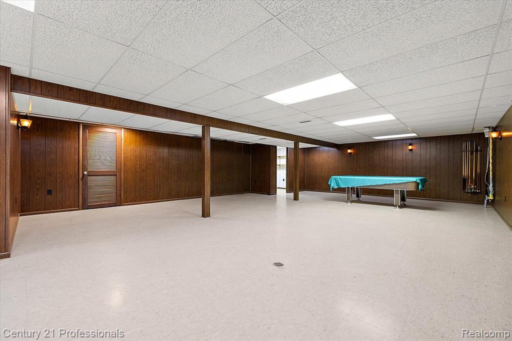 Finished basement featuring light flooring, wooden walls, billiards, and a drop ceiling