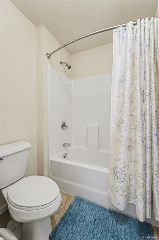 Bathroom with shower / bath combo with shower curtain and toilet